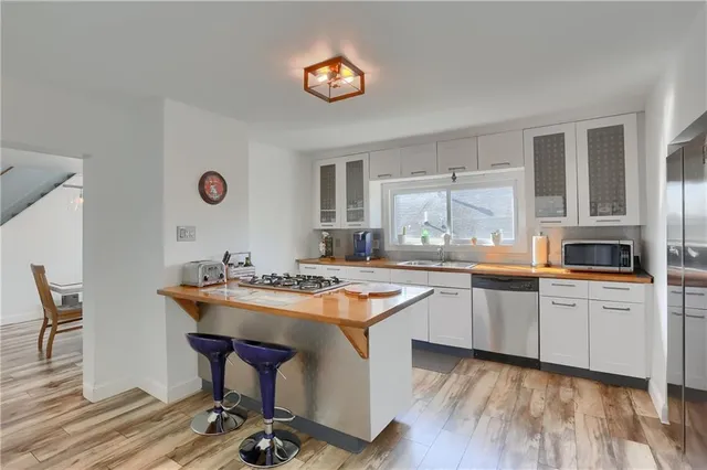 a kitchen with a sink a stove cabinets and wooden floor