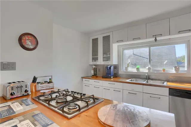 a kitchen with kitchen island granite countertop a sink a stove and wooden floors