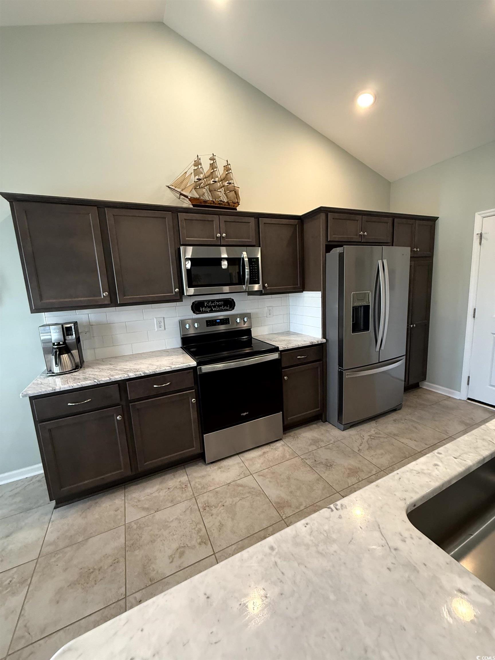 257 Maiden's Choice Drive Conway, SC 29527 - Photo 12 of 29 Kitchen with appliances with stainless steel finishes, dark brown cabinets, backsplash, light stone counters, and light tile patterned flooring