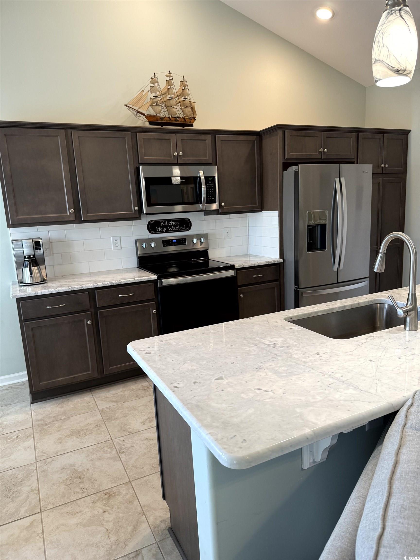 257 Maiden's Choice Drive Conway, SC 29527 - Photo 10 of 29 Kitchen with dark brown cabinetry, stainless steel appliances, decorative backsplash, light stone counters, and lofted ceiling