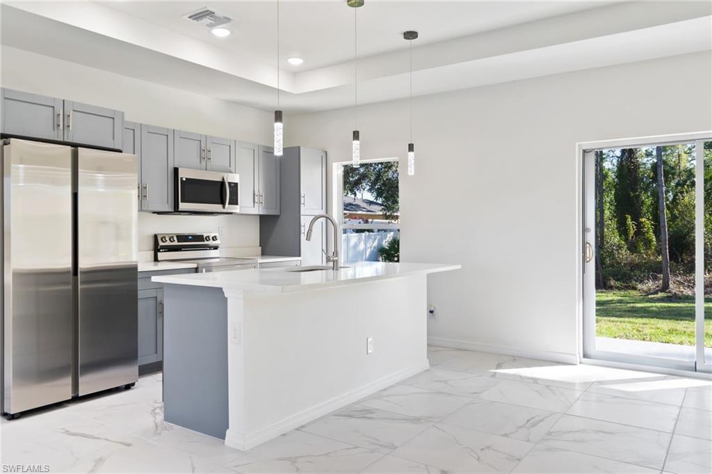 3707 Sunset Road Lehigh Acres, FL 33971 - Photo 1 of 16 a kitchen with stainless steel appliances a refrigerator sink and microwave
