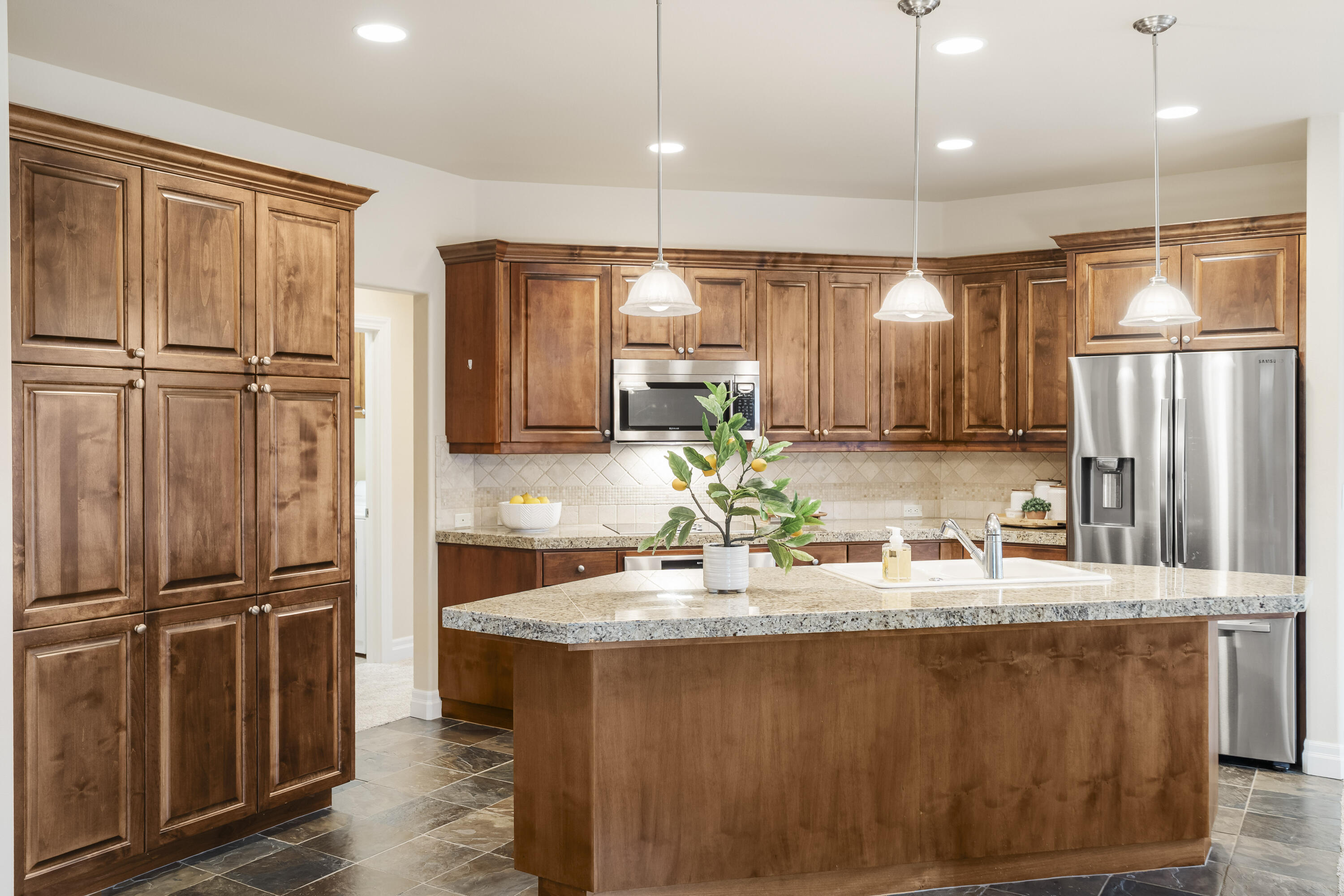 784 Ribbon Falls Road Redmond, OR 97756 - Photo 24 of 79 a kitchen with kitchen island granite countertop a refrigerator a sink and wooden cabinets