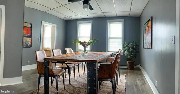 an empty room with wooden floor fan and windows