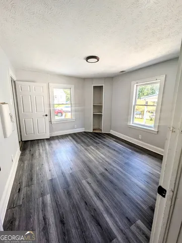 an empty room with wooden floor and windows
