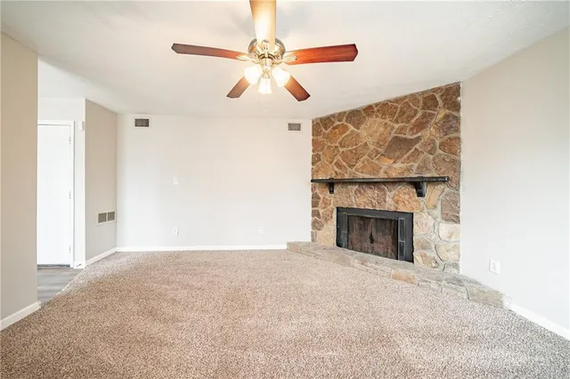 a view of empty room with fan and fireplace
