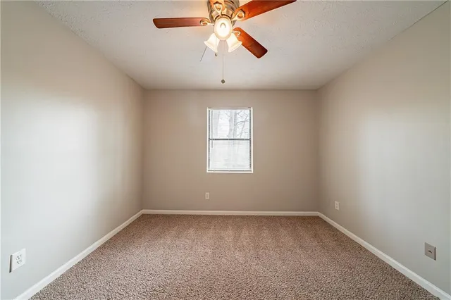 an empty room with a window and a chandelier fan