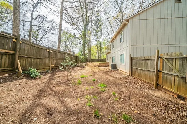 a backyard of a house with wooden fence and large trees
