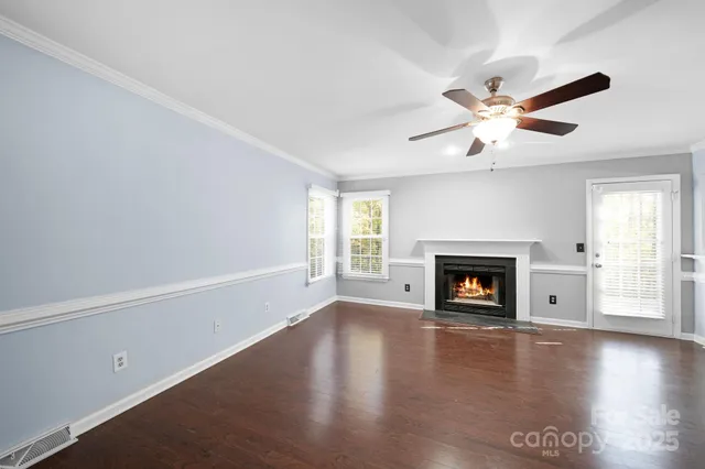 an empty room with windows fireplace and wooden floor
