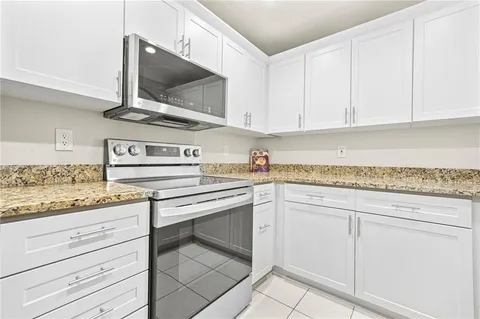 a kitchen with granite countertop white cabinets and white appliances