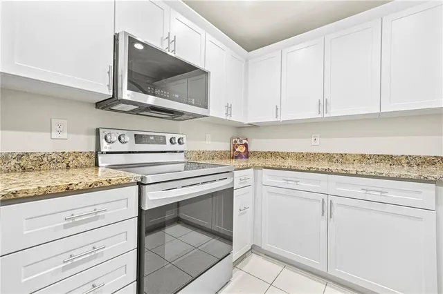a kitchen with granite countertop white cabinets and white appliances