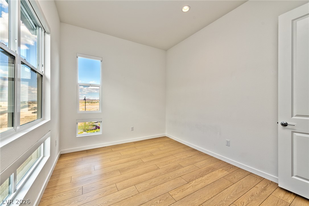 3327 Esker Rdg Avenue Henderson, NV 89044 - Photo 15 of 24 Hardwood flooring extends throughout this versatile space, bathed in natural light from multiple windows offering expansive views.