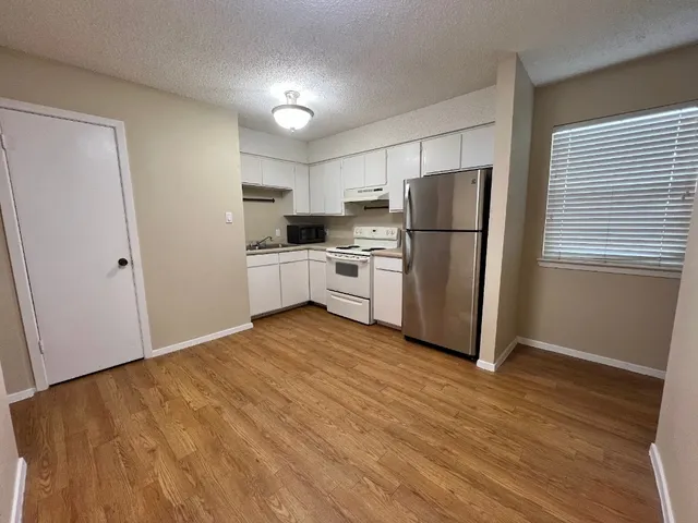 a kitchen with a refrigerator a stove top oven and white cabinets