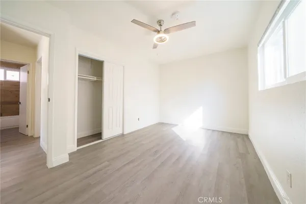 an empty room with wooden floor and a ceiling fan