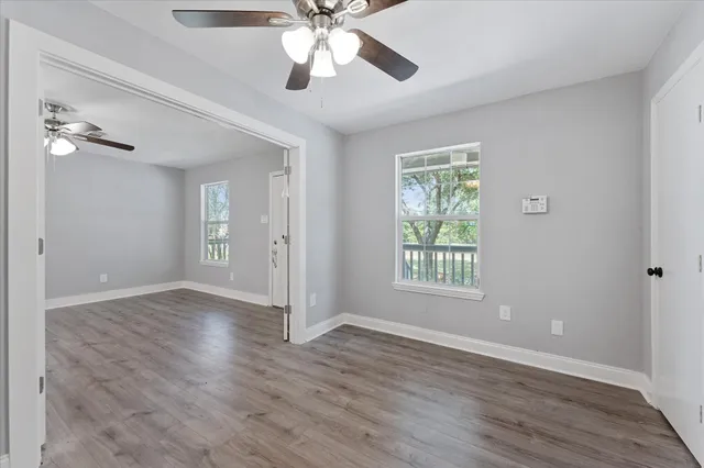 a view of an empty room with a window and wooden floor