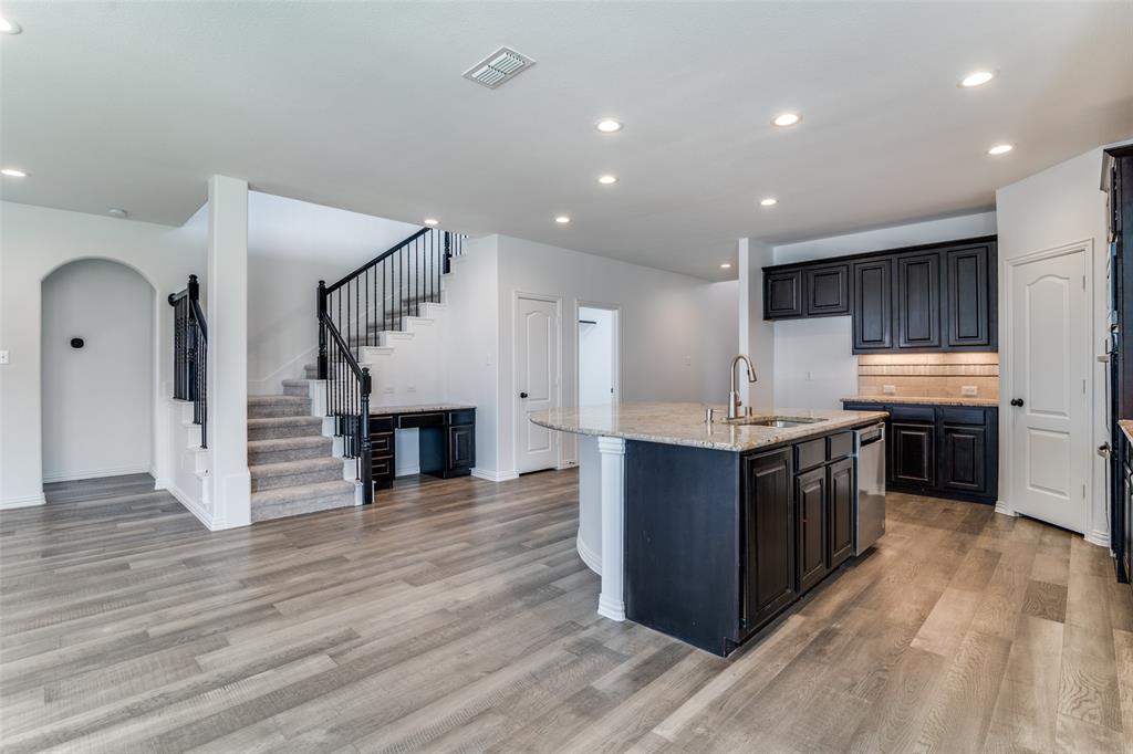 1215 Hundgate Way Forney, TX 75126 - Photo 11 of 38 Kitchen with a center island with sink, light stone counters, recessed lighting, arched walkways, and decorative backsplash