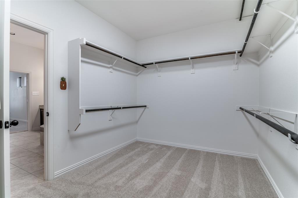 1215 Hundgate Way Forney, TX 75126 - Photo 20 of 38 Primary bedroom walk in closet with light colored carpet and three levels for clothes