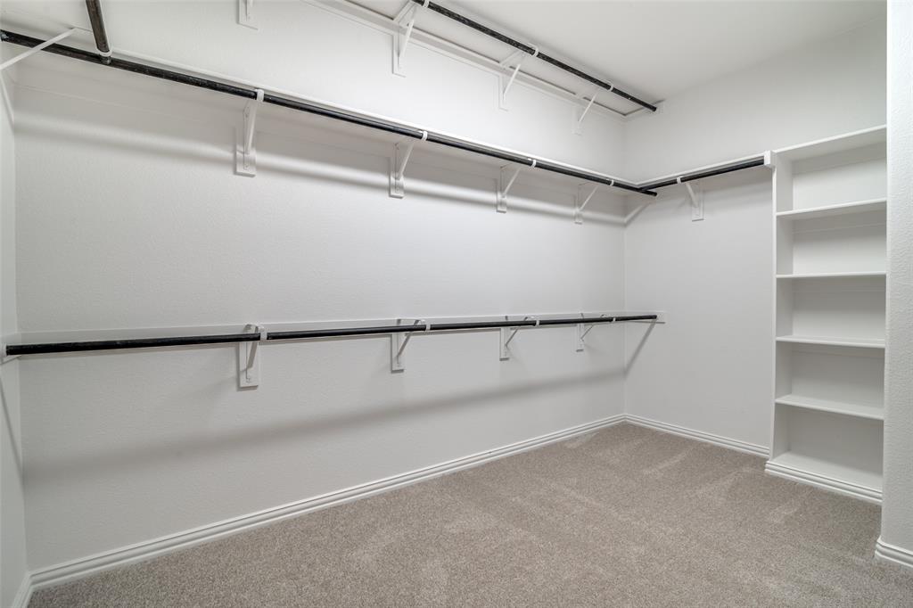 1215 Hundgate Way Forney, TX 75126 - Photo 21 of 38 Another view of the primary bedroom walk in closet with carpet floors and built in shelves