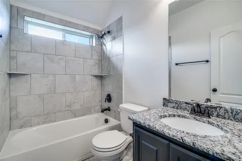 a bathroom with a granite countertop sink toilet mirror and bathtub