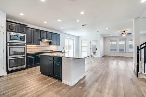 a kitchen with stainless steel appliances granite countertop a refrigerator and a stove top oven