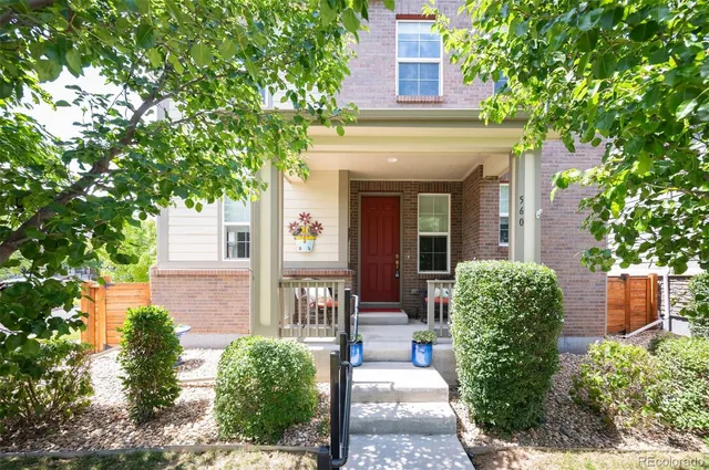 a view of a house with potted plants and a large tree
