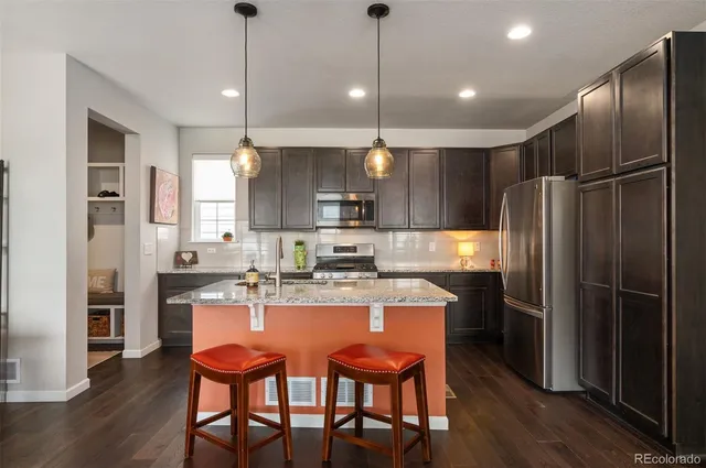 a kitchen with stainless steel appliances granite countertop a refrigerator a stove top oven a sink dishwasher and a refrigerator with wooden floor