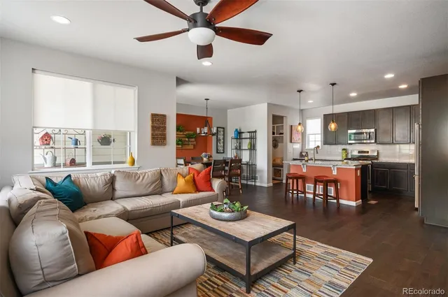 a living room with furniture kitchen view and a large window