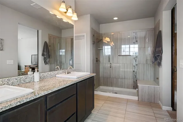 a bathroom with a granite countertop sink a toilet a mirror and shower