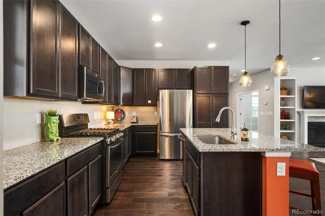 a kitchen with stainless steel appliances granite countertop a sink a stove and refrigerator