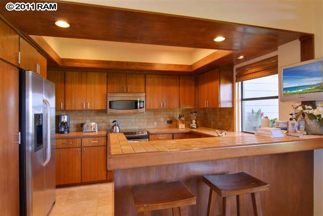 100 Ridge Road, Unit 2814 Lahaina, HI 96761 - Photo 5 of 30 a kitchen with a table chairs refrigerator and cabinets