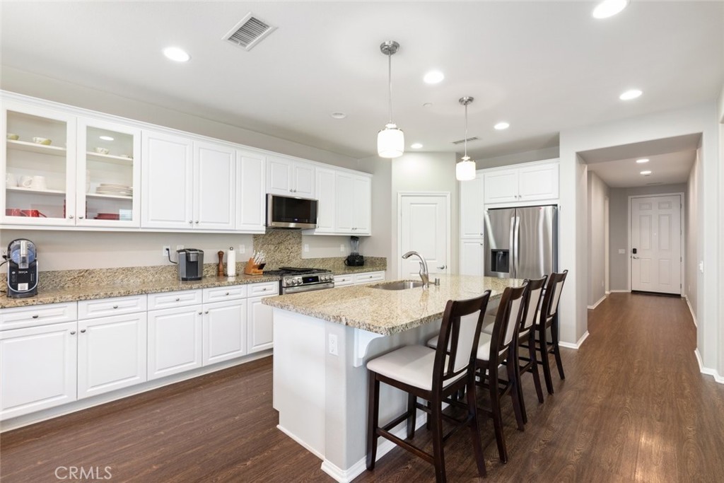 25451 Jack Rabbit Lane Corona, CA 92883 - Photo 12 of 75 a kitchen with stainless steel appliances granite countertop a stove top oven a sink dishwasher a dining table and chairs with wooden floor