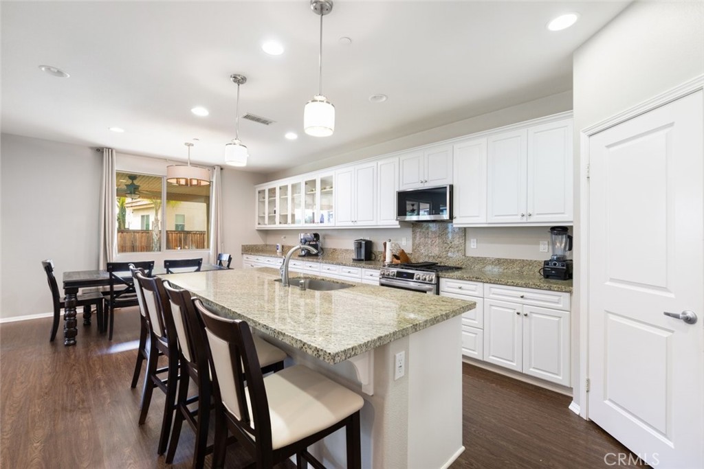 25451 Jack Rabbit Lane Corona, CA 92883 - Photo 13 of 75 a kitchen with a dining table chairs and wooden floor