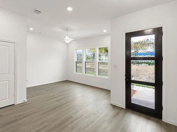 an empty room with wooden floor and windows