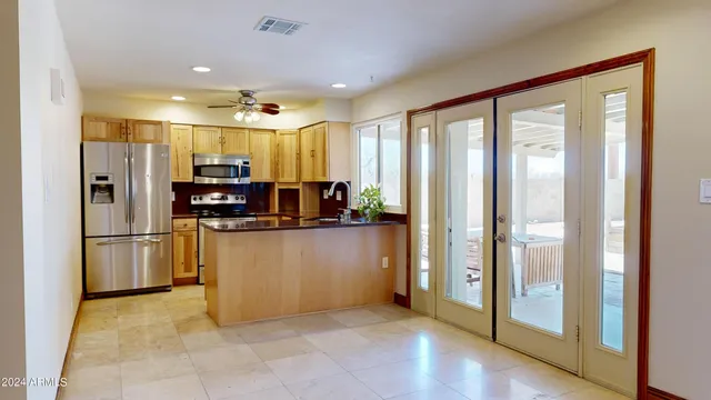 a view of kitchen with stainless steel appliances granite countertop a refrigerator and a stove top oven