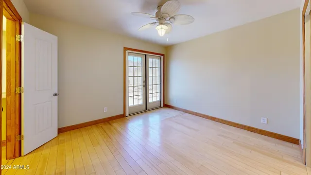 an empty room with wooden floor chandelier fan and windows