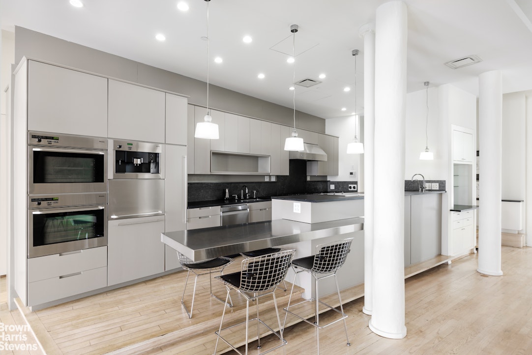 129 Greene Street, Unit 2 Manhattan, NY 10012 - Photo 4 of 12 a kitchen with stainless steel appliances kitchen island granite countertop a refrigerator and a stove top oven