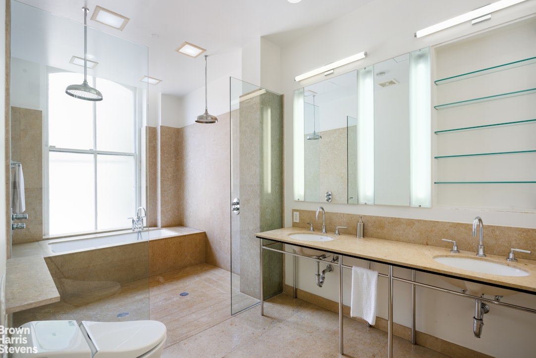 129 Greene Street, Unit 2 Manhattan, NY 10012 - Photo 6 of 12 a spacious bathroom with a double vanity sink mirror and toilet