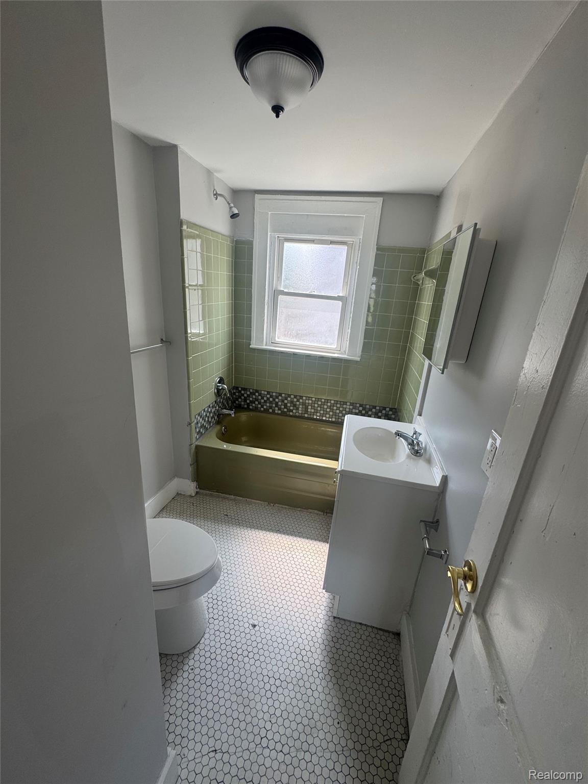 2176 Springle Street Detroit, MI 48215 - Photo 9 of 9 Bathroom featuring a window, green tiled walls, and white hexagonal floor tiling