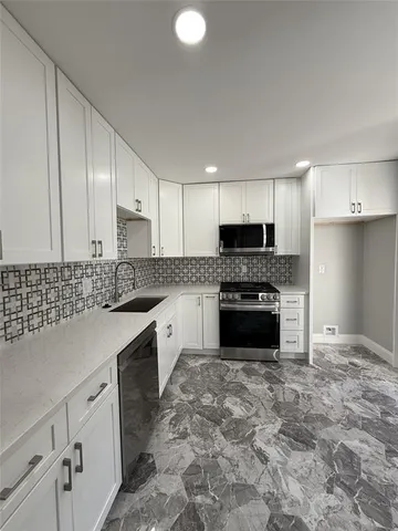 a kitchen with granite countertop a stove sink and cabinets