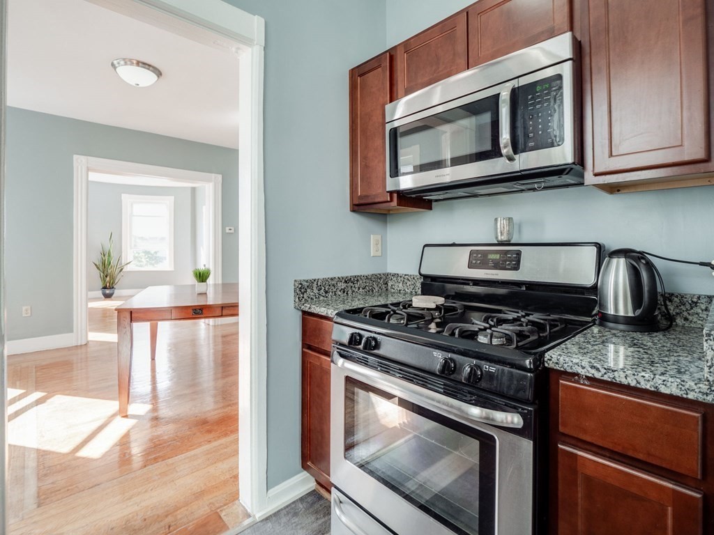 38 Cherry Street, Unit 2 Lynn, MA 01902 - Photo 7 of 40 a kitchen with granite countertop wooden cabinets stainless steel appliances and a wooden floor