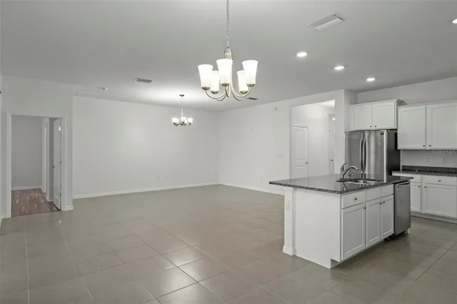 a kitchen with stainless steel appliances granite countertop a sink a stove a refrigerator a center island and cabinets