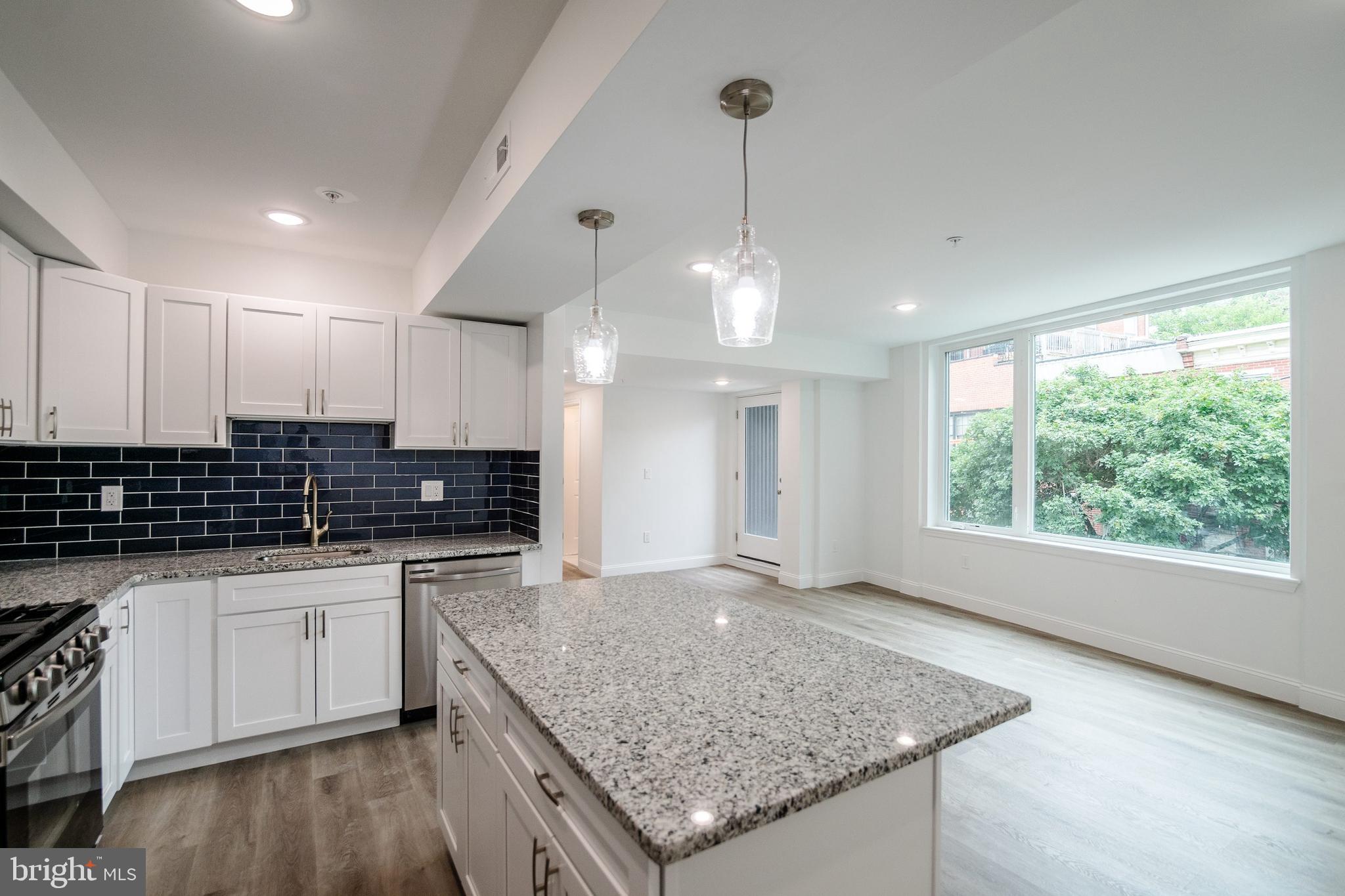 129 Washington Avenue, Unit B Philadelphia, PA 19147 - Photo 4 of 18 a kitchen with stainless steel appliances granite countertop a sink a stove and a wooden floor
