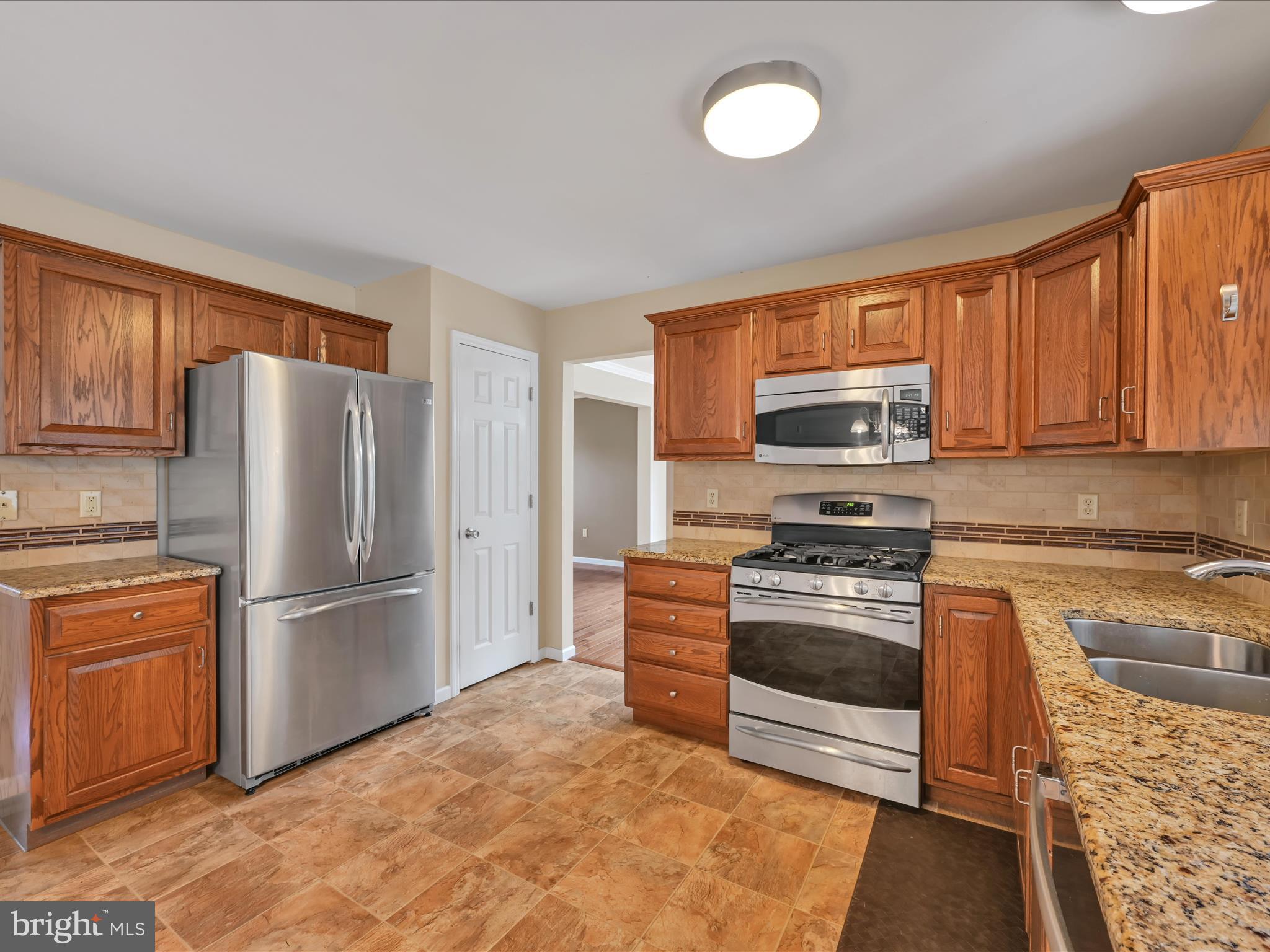 2602 Andrew Drive Sinking Spring, PA 19608 - Photo 21 of 47 a kitchen with granite countertop a refrigerator stove and microwave