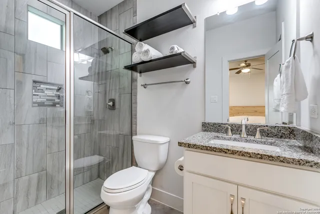 a bathroom with a granite countertop sink toilet and shower