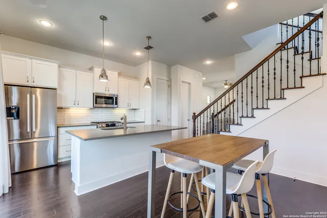 a kitchen with stainless steel appliances granite countertop a kitchen island a stove a dining table and chairs