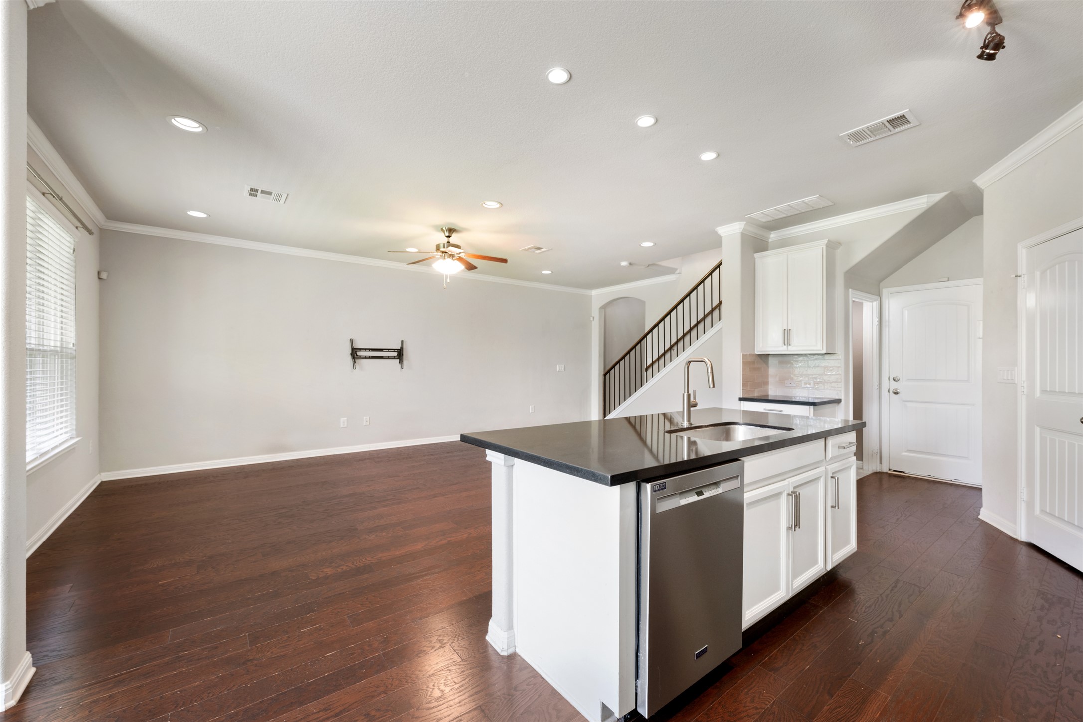 211 Parable Cove Pflugerville, TX 78660 - Photo 15 of 40 Kitchen island featuring a stainless steel sink with gooseneck faucet, an integrated dishwasher, and dark countertops