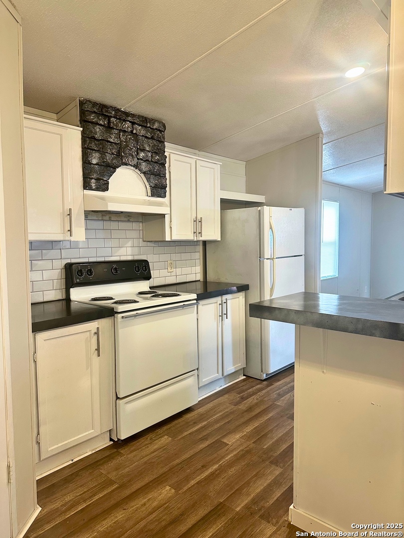 310 Duck Street Pleasanton, TX 78064 - Photo 4 of 6 a kitchen with granite countertop white cabinets and white appliances