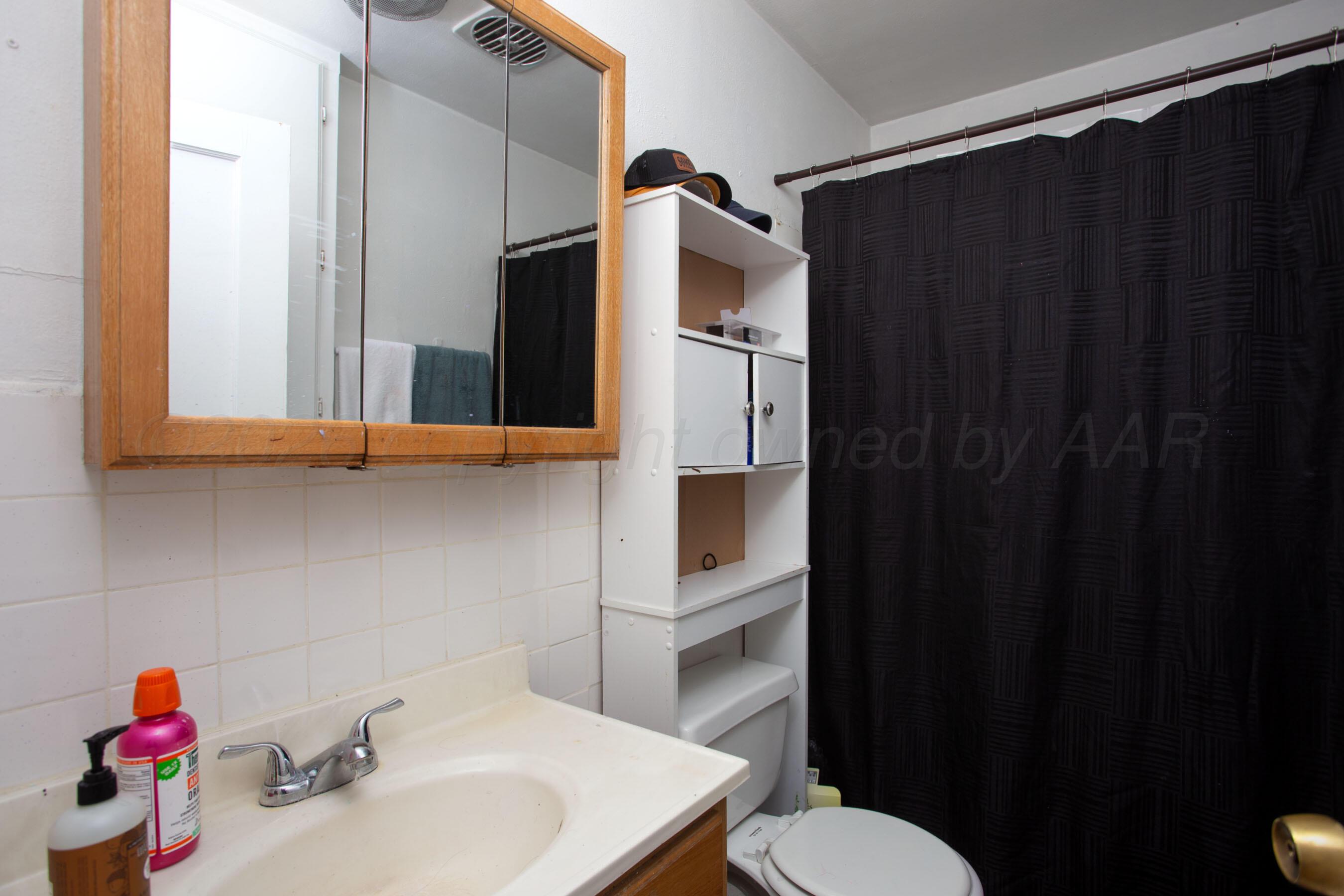 4003 South Van Buren Street Amarillo, TX 79110 - Photo 13 of 25 a bathroom with a sink and a mirror