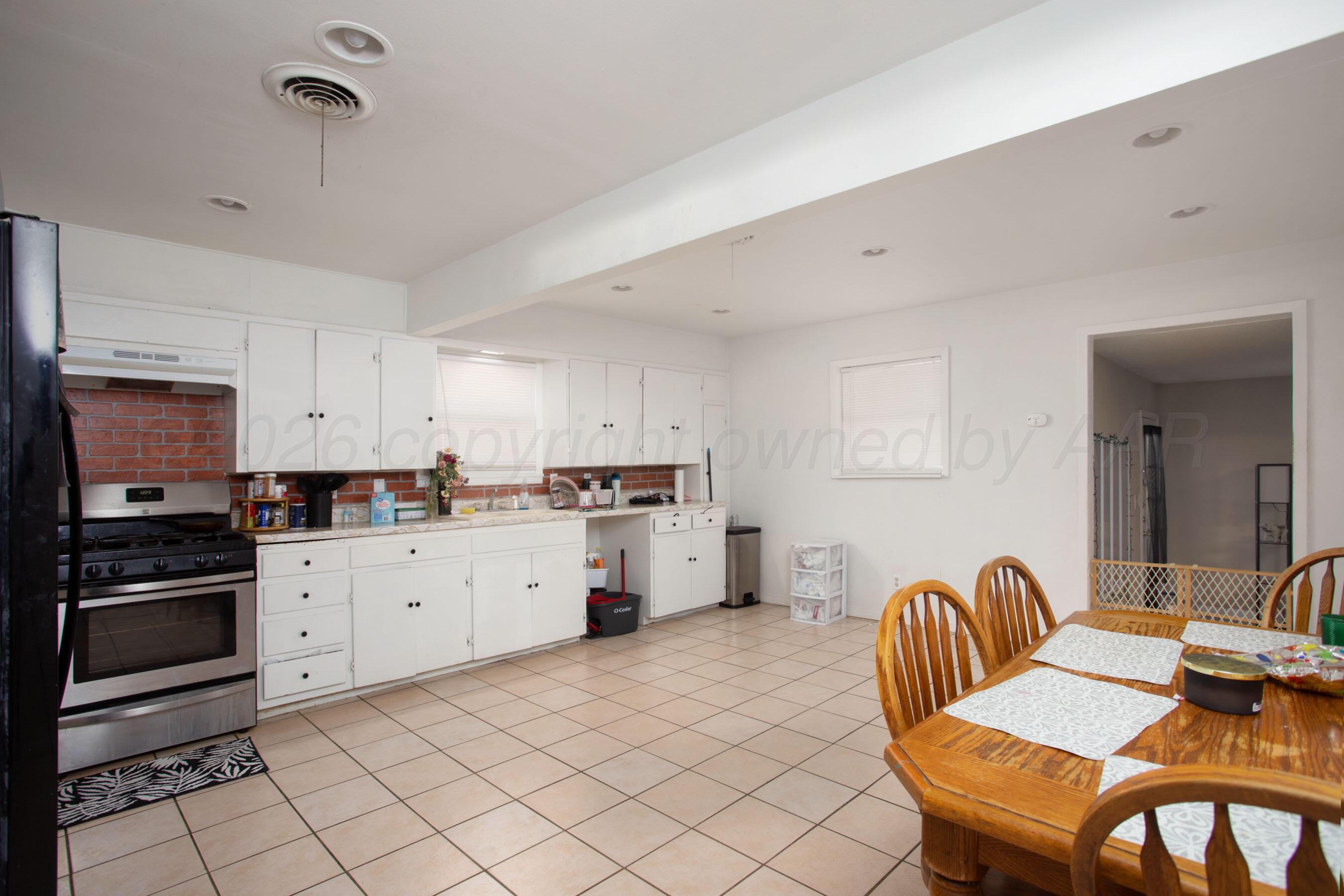 4003 South Van Buren Street Amarillo, TX 79110 - Photo 16 of 25 a kitchen with stainless steel appliances kitchen island granite countertop a refrigerator a stove a sink dishwasher with a dining table and chairs
