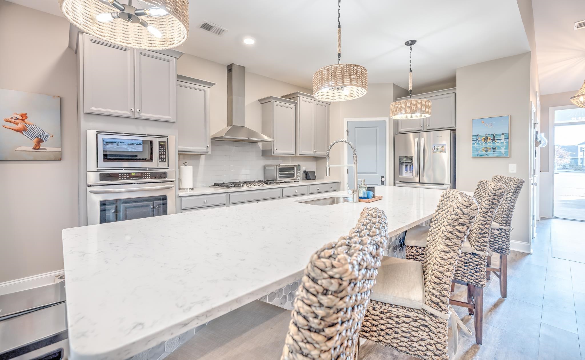 2488 Goldfinch Drive Myrtle Beach, SC 29577 - Photo 5 of 38 Kitchen with light stone countertops, a breakfast bar area, stainless steel appliances, tasteful backsplash, and wall chimney range hood