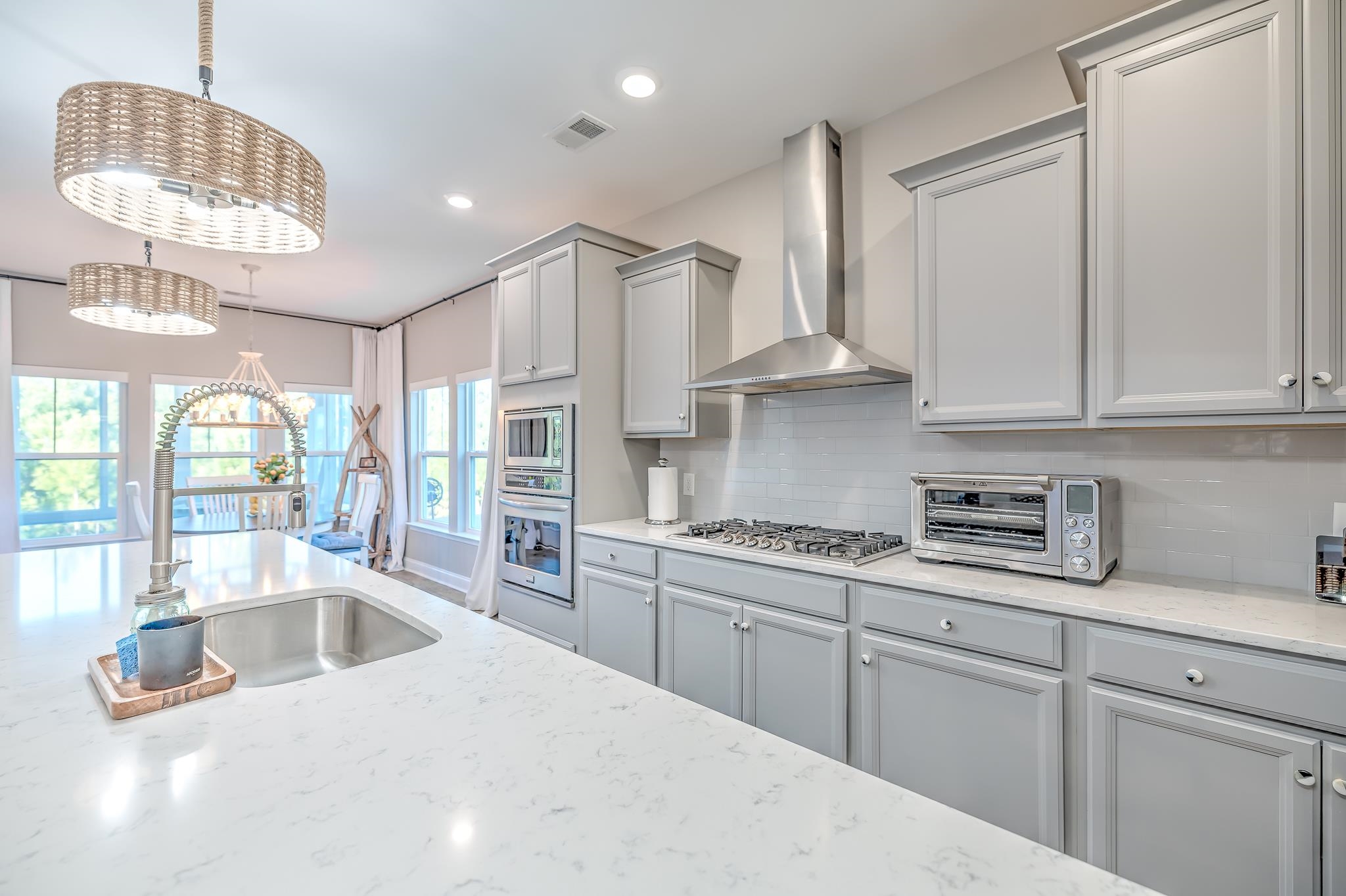 2488 Goldfinch Drive Myrtle Beach, SC 29577 - Photo 6 of 38 Kitchen featuring wall chimney range hood, light stone counters, stainless steel appliances, decorative backsplash, and decorative light fixtures